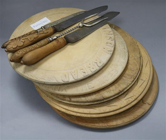 Five carved bread boards plus two carved handled bread knives and another and a bread fork largest diameter 30cm